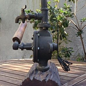 Lámpara de mesa artesanal de estilo rústico La base está compuesta por un robusto medio tronco de madera noble con su corteza natural texturizada, sobre el cual se monta el cuerpo principal de una antigua bomba de agua manual giratorio de hierro fundido No. 2 Allwilen Original Pumpe. Incorpora detalles de fontanería vintage como cañerías de hierro y una canilla de bronce decorativo en el eje. En Muy bueno estado de Conservación. Medidas Sin pantalla: Alto 72 cm - Base Largo 33 cm - imagen 5