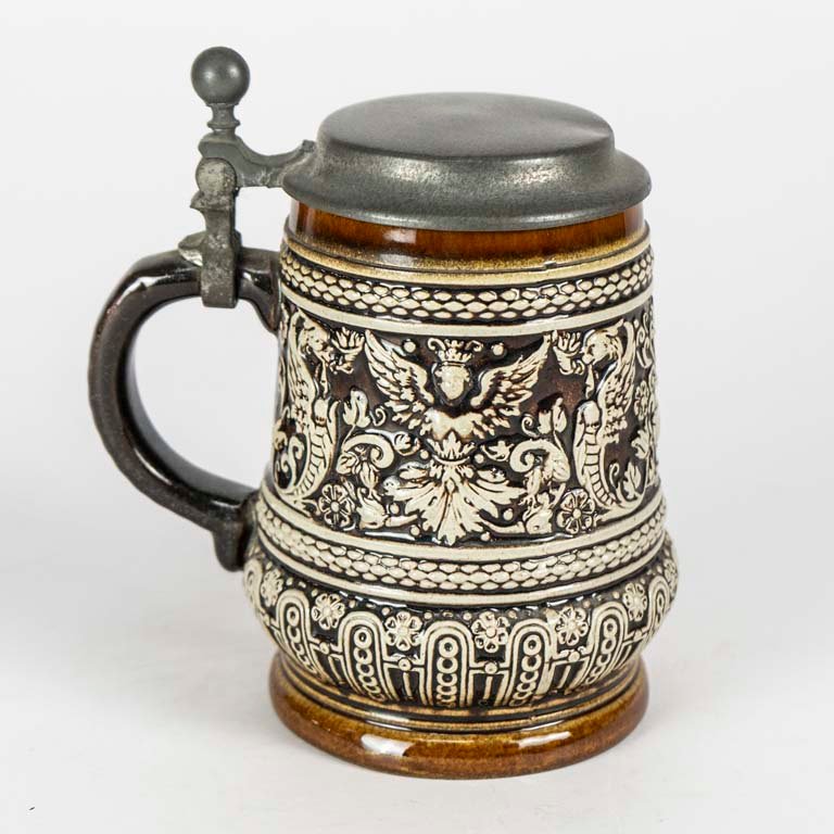 Lote siguiente: Jarra de cerveza de cerámica con diseño en relieve y tapa de peltre