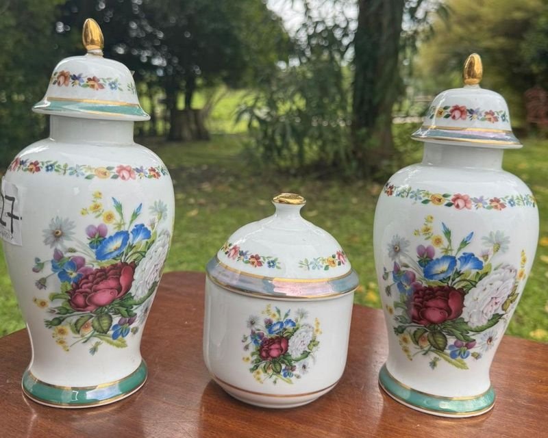 1 juego en porcelana española V.P compuesto por 2 jarrones tipo potiche y 1 alajero con tapa. Su diseño es fino y elegante con montivos florales y guardas al rededor de las piezas montadas sobre un platillo (24 y 13 las medidas)