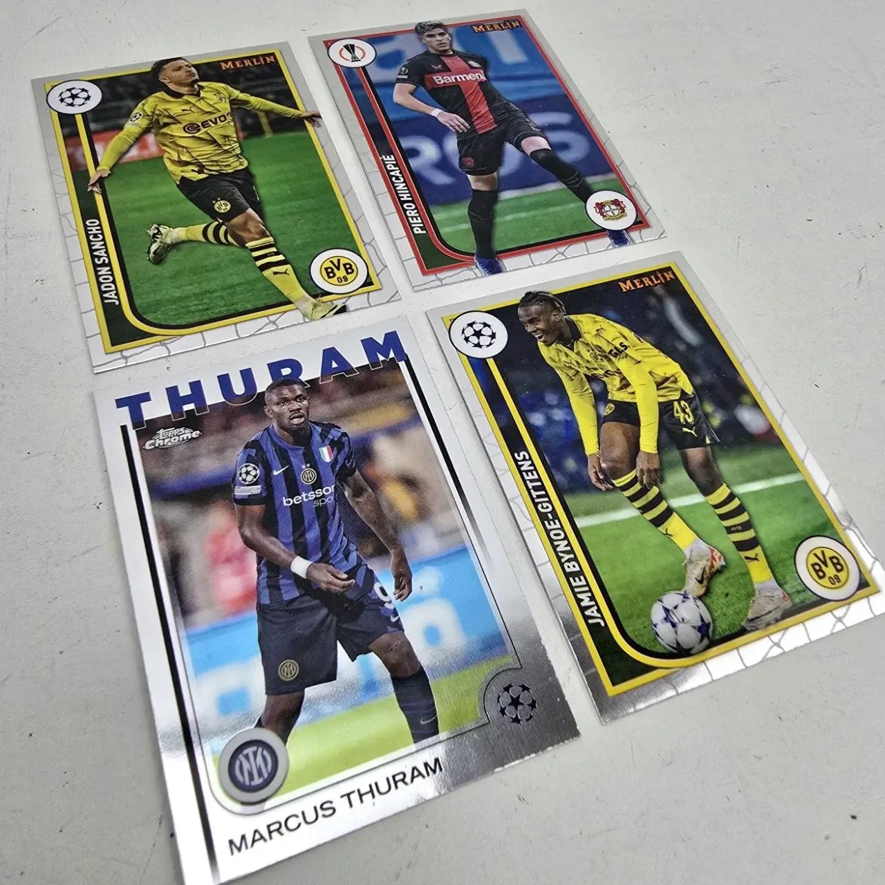 Lote de 4 Tarjetas de Fútbol Topps y Merlin: Jadon Sancho, Piero Hincapié, Marcus Thuram, Jamie Bynoe-Gittens