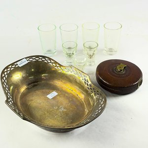 Lote siguiente: Nueve piezas, centro en metal oval ala calada, vasos licor y cinta métrica (con detalles)