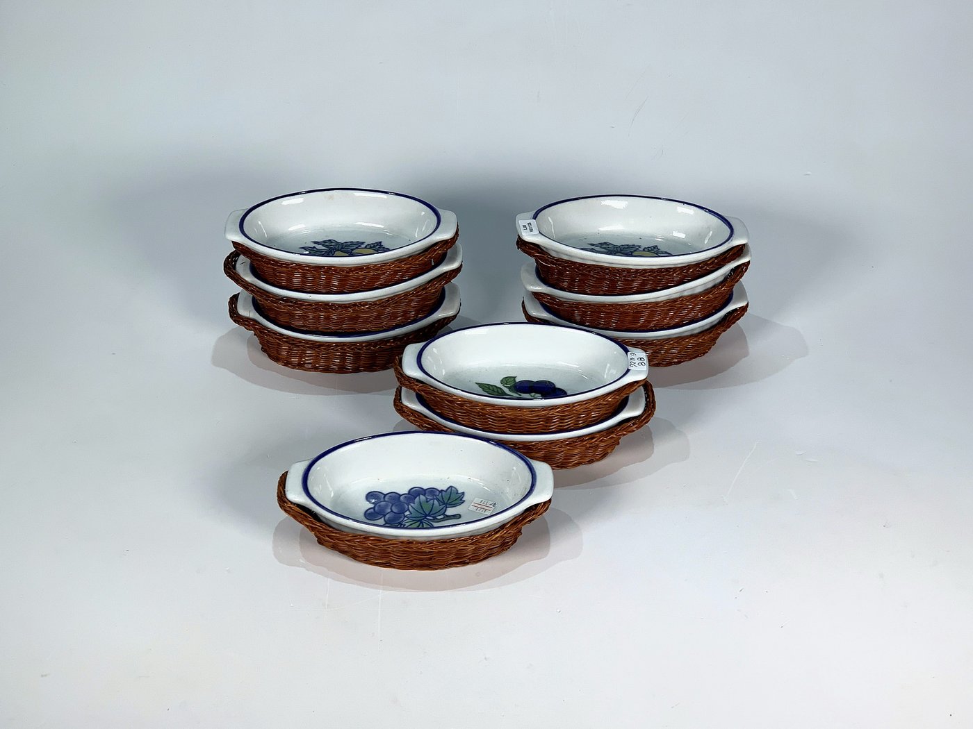 Nueve Cazuelas Ovales de Losa Blanca con Soporte de Ratán y Decoración Frutal