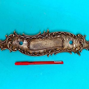 Lote siguiente: Antigua placa de manoton de puerta en bronce de muy buena calidad de fundición francesa. Tiene buzonera. Largo 30 cm x 8 cm.