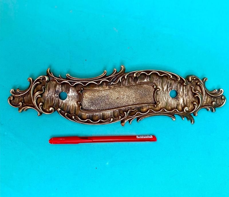 Antigua placa de manoton de puerta en bronce de muy buena calidad de fundición francesa. Tiene buzonera. Largo 30 cm x 8 cm.