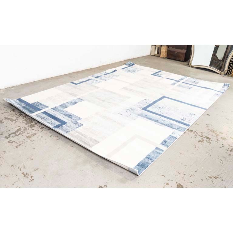 Alfombra acrílica con diseños geométricos en colores celeste, azul, gris y blanco