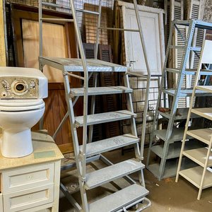 Lote siguiente: Una escalera metálica rodante color gris con detalle en ruedas seis escalones