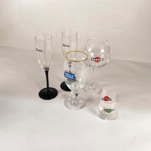 Lote siguiente: Set de 5 piezas de cristalería con monogramas: Martini, Stella Artois y Freixenet