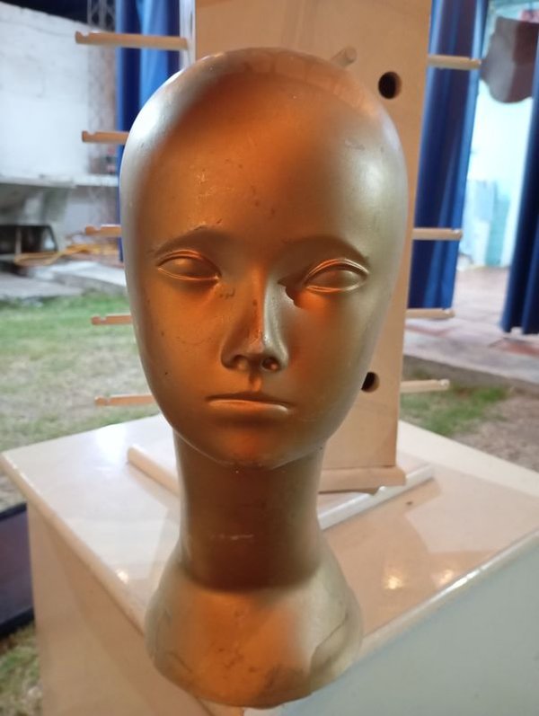 Cabeza de maniquí dorada en pie
