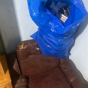 Lote siguiente: Sillón de cuero marrón con bolsa de perchas y ropa