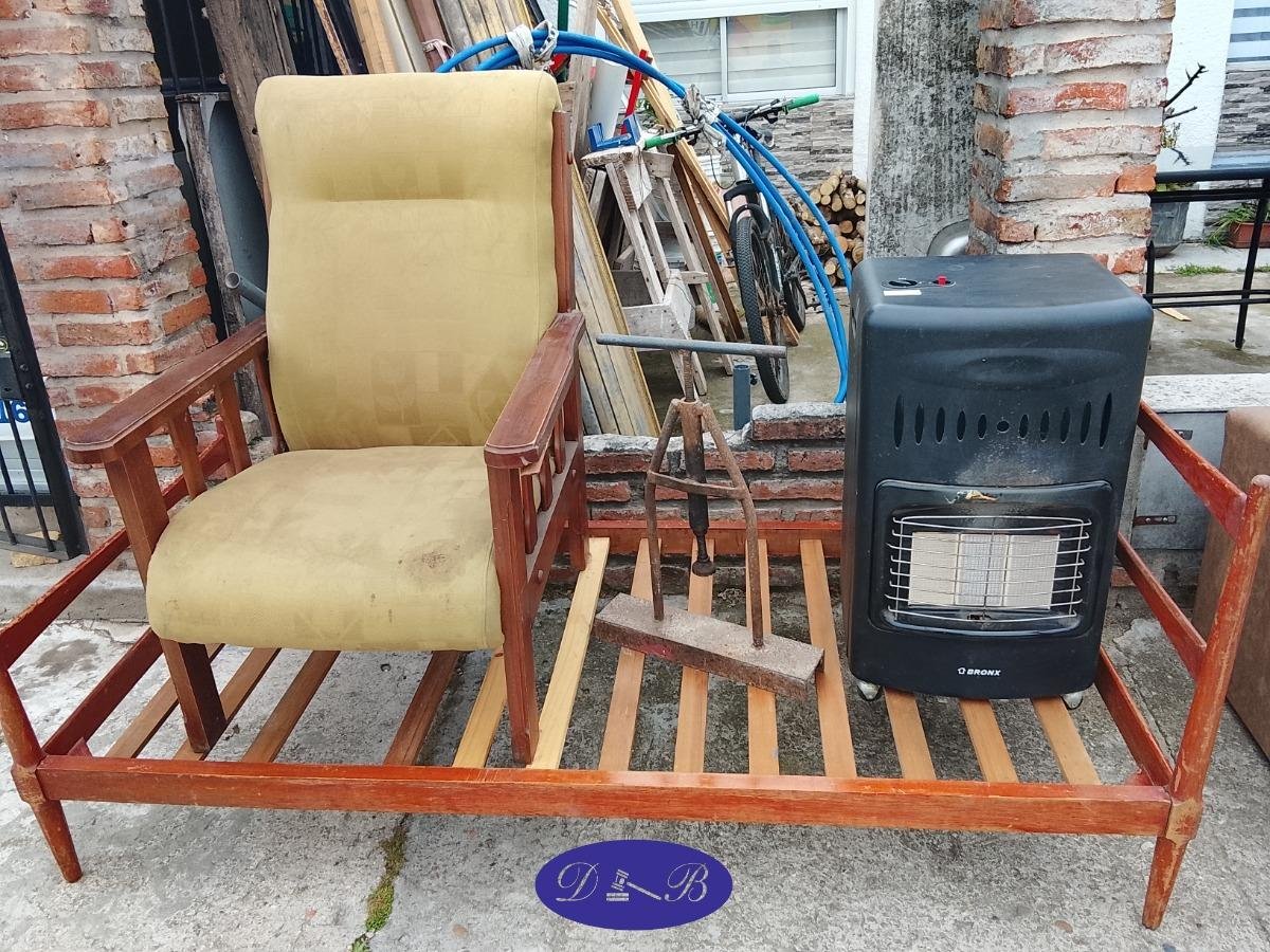 Cama de una plaza, sillón de madera, estufa a gas y prensa