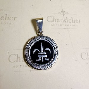 Lote siguiente: Dije Circular con Flor de Lis en Metal Blanco y Fondo Negro