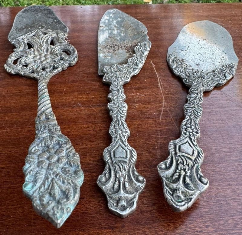 tres palas de servir con diferentes diseños en metal plateado labrado