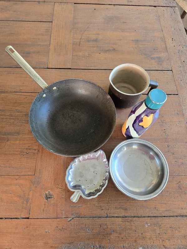 Wok de metal, termo decorado, platillo y jarro de leche