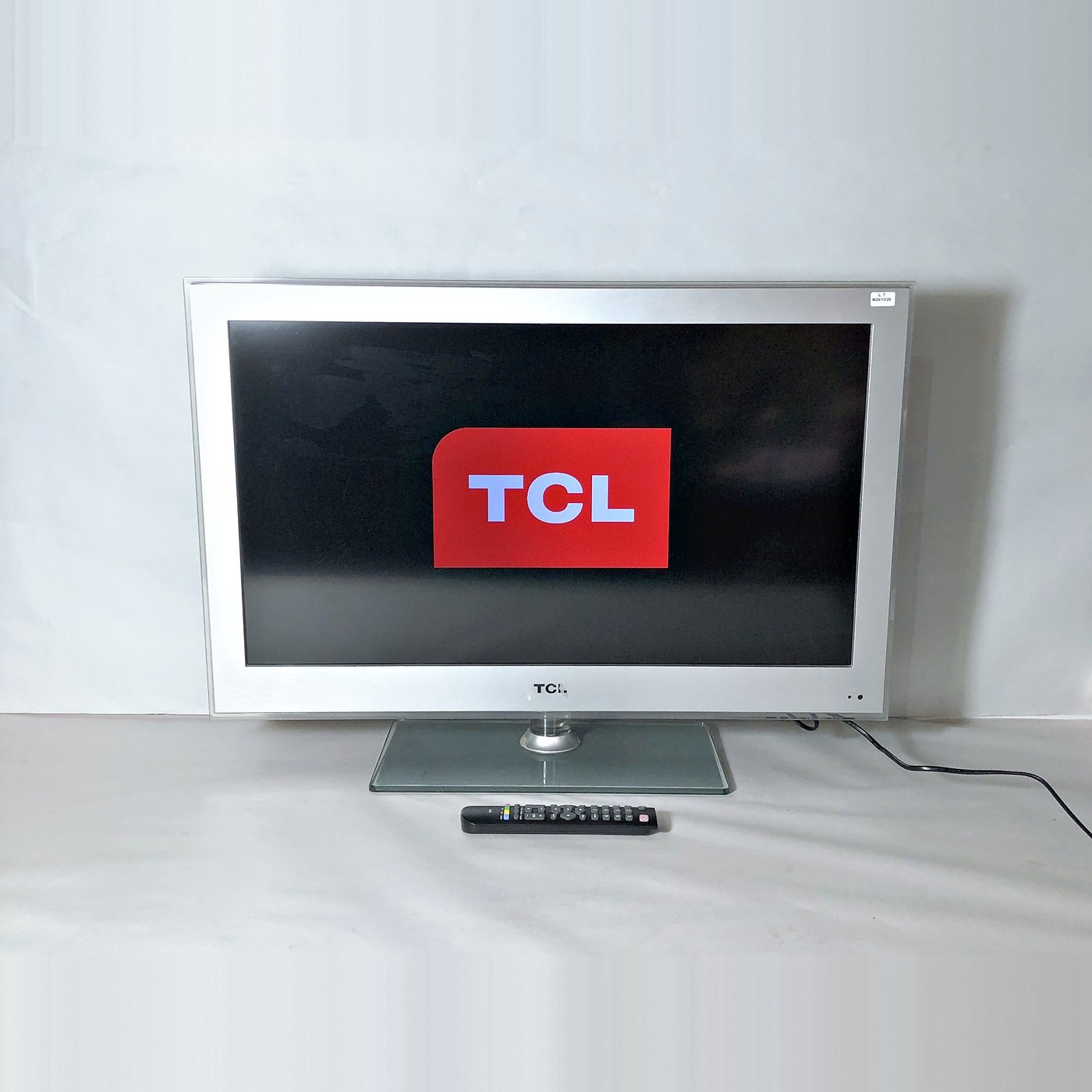 Televisor TCL de 32 pulgadas con control remoto, funcionando