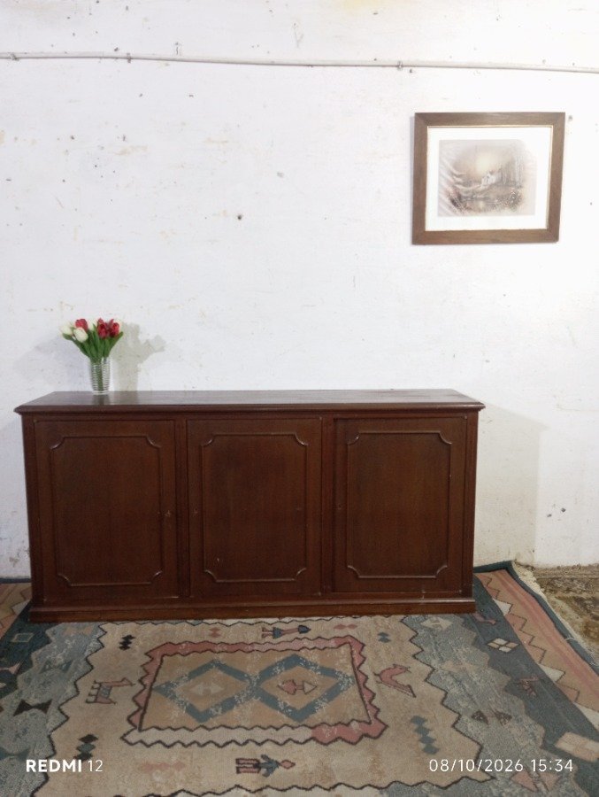 Aparador bajo de madera oscura con tres puertas y molduras