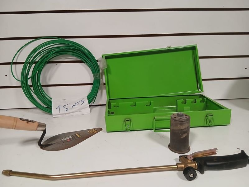 Valija metálica verde con herramientas: cuchara de albañil, soplete y rollo pasacables