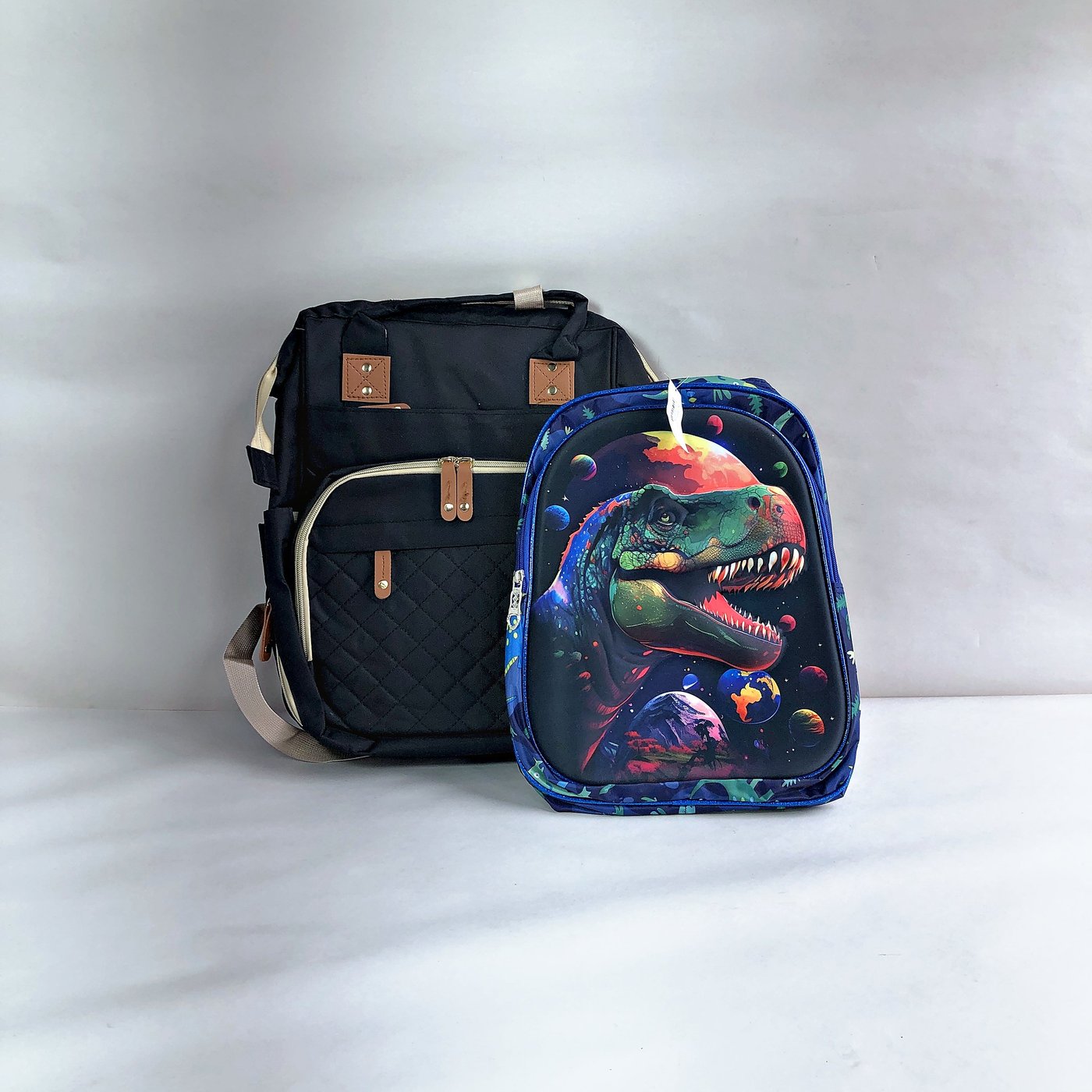 Par de Mochilas Infantiles: Negra Maternal y Azul con Dinosaurios y Espacio