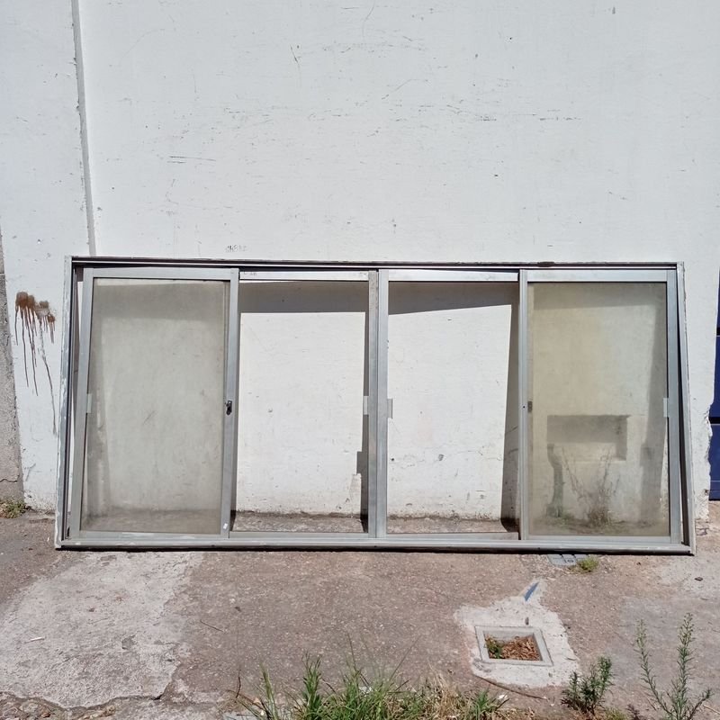 Lote siguiente: Ventana de aluminio con cuatro hojas corredizas, a dos de ellas le falta el vidrio