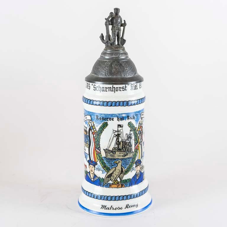Lote siguiente: Jarra de cerveza de porcelana con tapa de metal y diseño decorativo