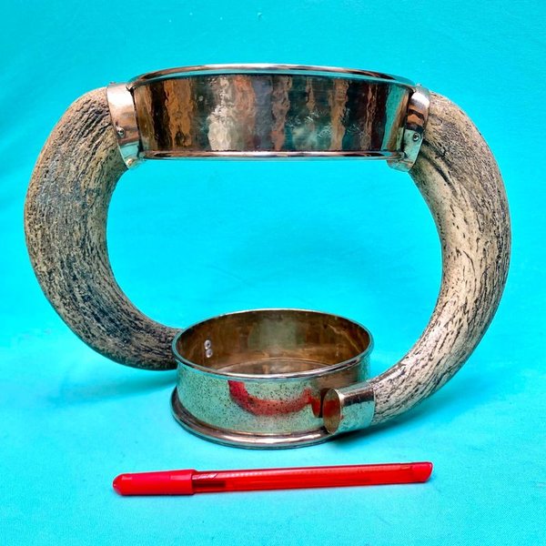 Adorno atesanal decorativo portabotellas de vino realizada en alpaca bañada en plata con asas en astas de chivo u otro.