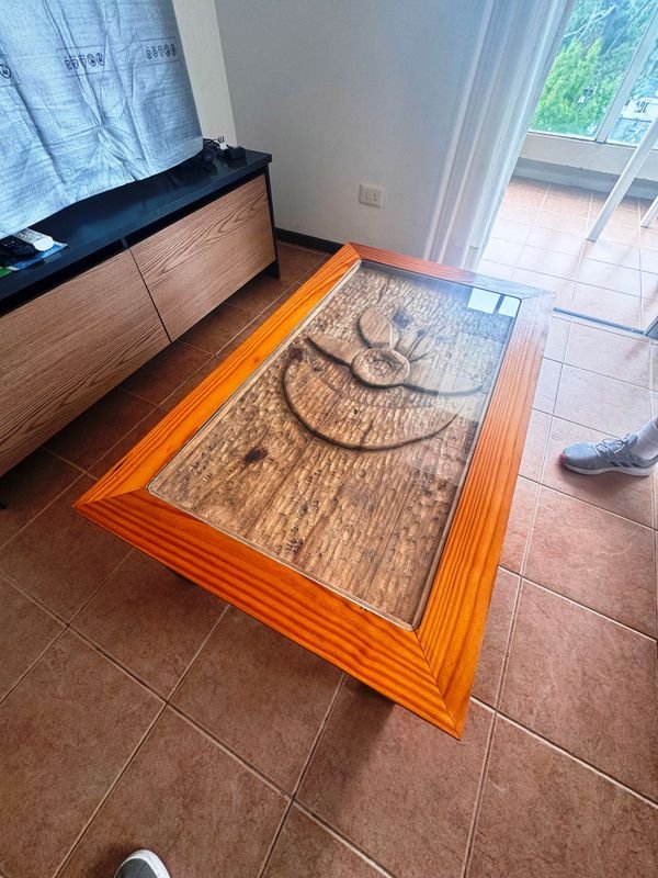 Mesa ratona de madera con diseño tallado y superficie de vidrio