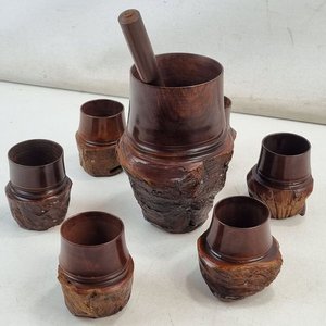 Lote siguiente: L 014 - 8 piezas - Excepcional juego de licorera, revolvedor y 6 vasos vintage esculpidos en madera noble artesanal con corteza natural (excelente estado estructural general de época con pátina natural, un vaso presenta leve fisura superficial por resequedad en su base que no afecta su uso)