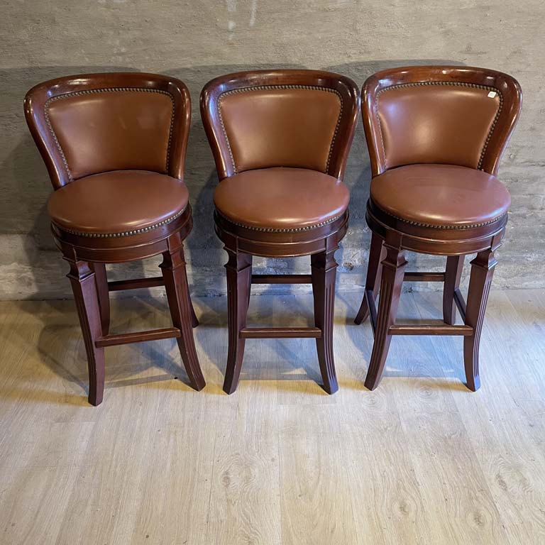 Tres banquetas altas en cuero con asientos tapizados y patas de madera