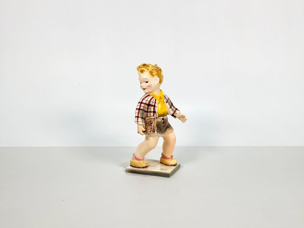 Lote siguiente: Figura en loza austriaca con motivo de niño con portafolio