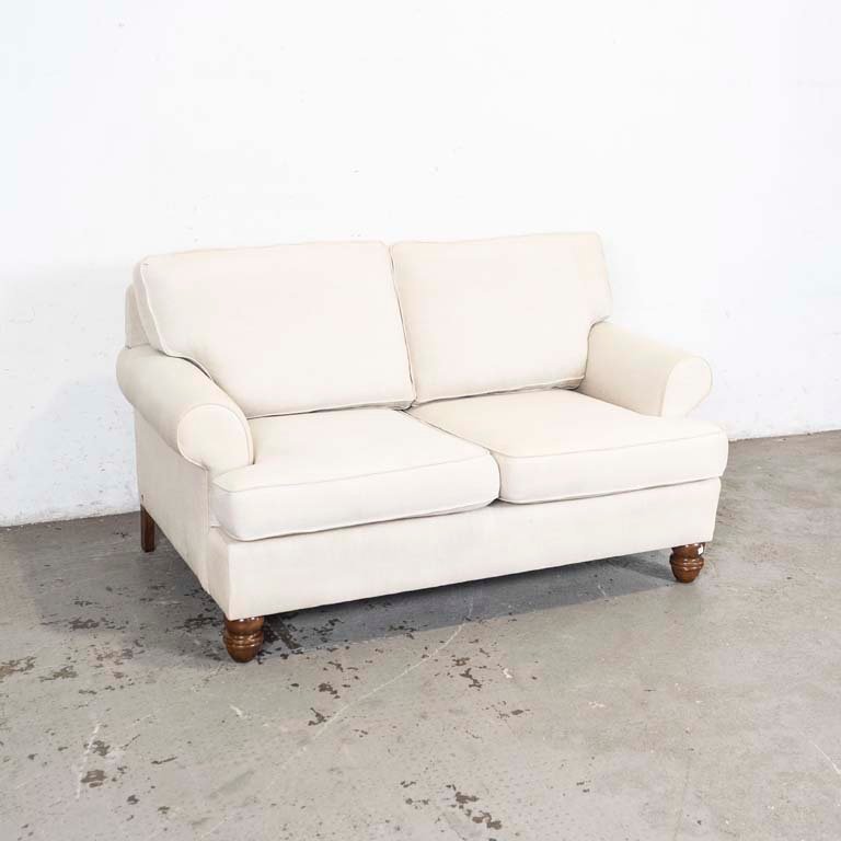 Lote anterior: Sofá de dos cuerpos tapizado en tela beige, con patas torneadas