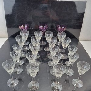 Lote siguiente: L 294 - 23 Piezas - Importante lote de 23 copas de licor en cristal tallado con base redonda, incluyendo 4 copas con detalle de color en tonos violetas