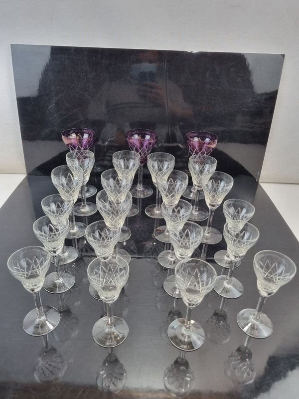 L 294 - 23 Piezas - Importante lote de 23 copas de licor en cristal tallado con base redonda, incluyendo 4 copas con detalle de color en tonos violetas