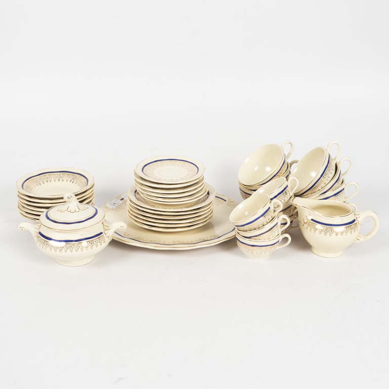 34 Piezas de loza uruguaya Versailles. Fondo beige decorado con azul y dorado. Azucarero con cascadura, platito de café con fisura, taza de té con cascadura - Medidas: Taza de té 10x5cm