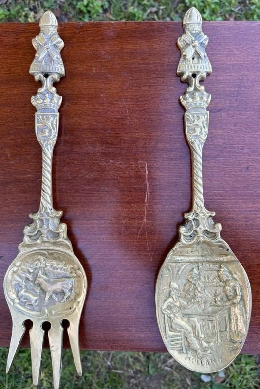 1 par de utensillos decorativos en bronce macizo de gran tamaño y peso conmemorativos de holanda (tenedor vaca con granjero evocando la vida rural y la agricultura, con un molino en su otro extremo y un escudo heraldico, cuchara evoca una escena en un meson o taberna lugares tipicos de las zonas rurales en los siglos 16 y 17)