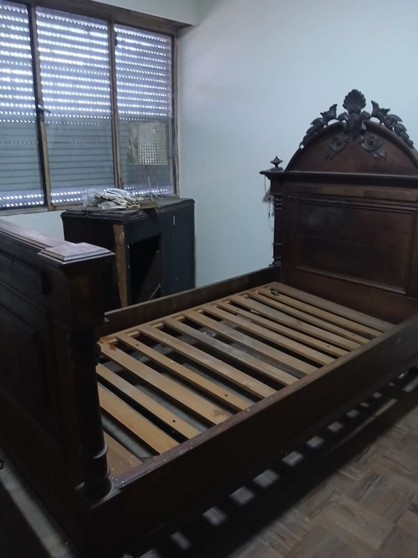 Cama antigua de madera con ventilador metálico