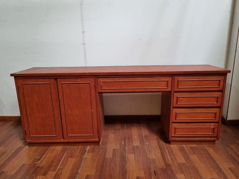 Escritorio de madera rojiza con puertas y cajones