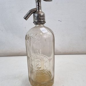 Lote siguiente: L 339 - 1 Pieza - Antiguo sifón de soda de vidrio con cabezal de metal, diseño vintage con relieves decorativos y texto grabado - Ideal para coleccionistas o decoración