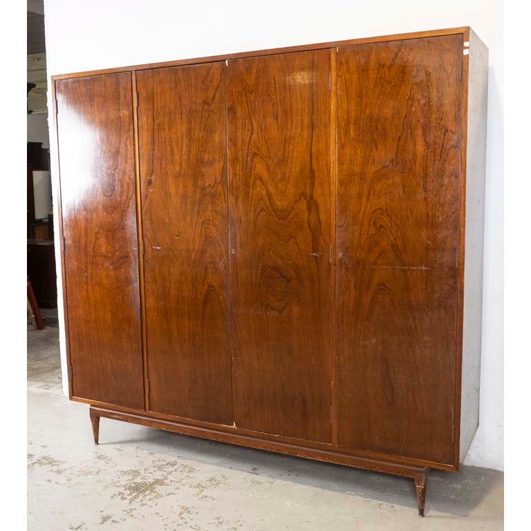 Ropero americano de cuatro puertas. Interior con espejo, cofre y tres cajones. Averías en el enchapado, detalles en la madera y en el lustre. Faltan estantes y tiradores. - Medidas: 220 x 59 x 212cm