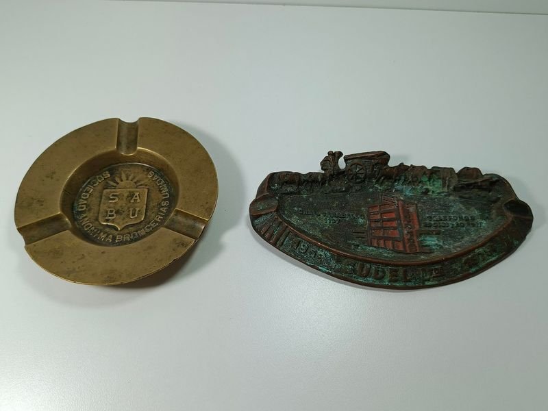 Lote anterior: Par de ceniceros en bronce con logotipos y monumento a la carreta