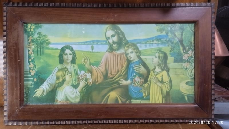 La imagen muestra un cuadro antiguo con un marco de madera rectangular que enmarca una lámina litográfica religiosa de estilo clásico