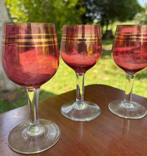 3 copas en cristal de color rojo rubi y anillos dorados