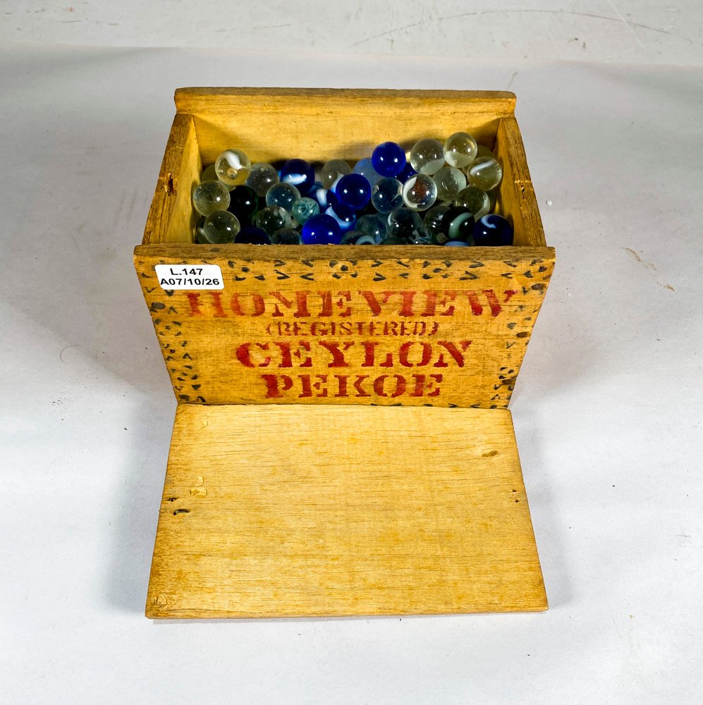 Caja de madera antigua con bolitas de vidrio de colección