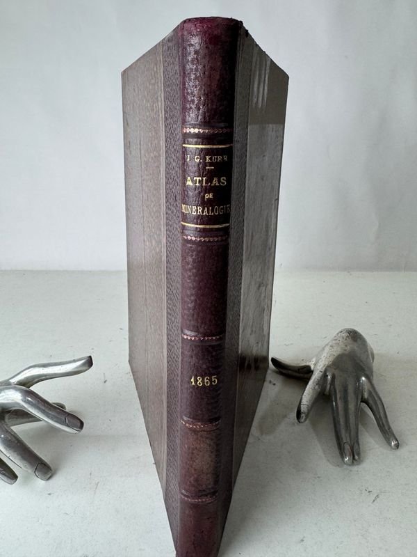 Lote anterior: Libro antiguo de mineralogía con una mano en la cubierta
